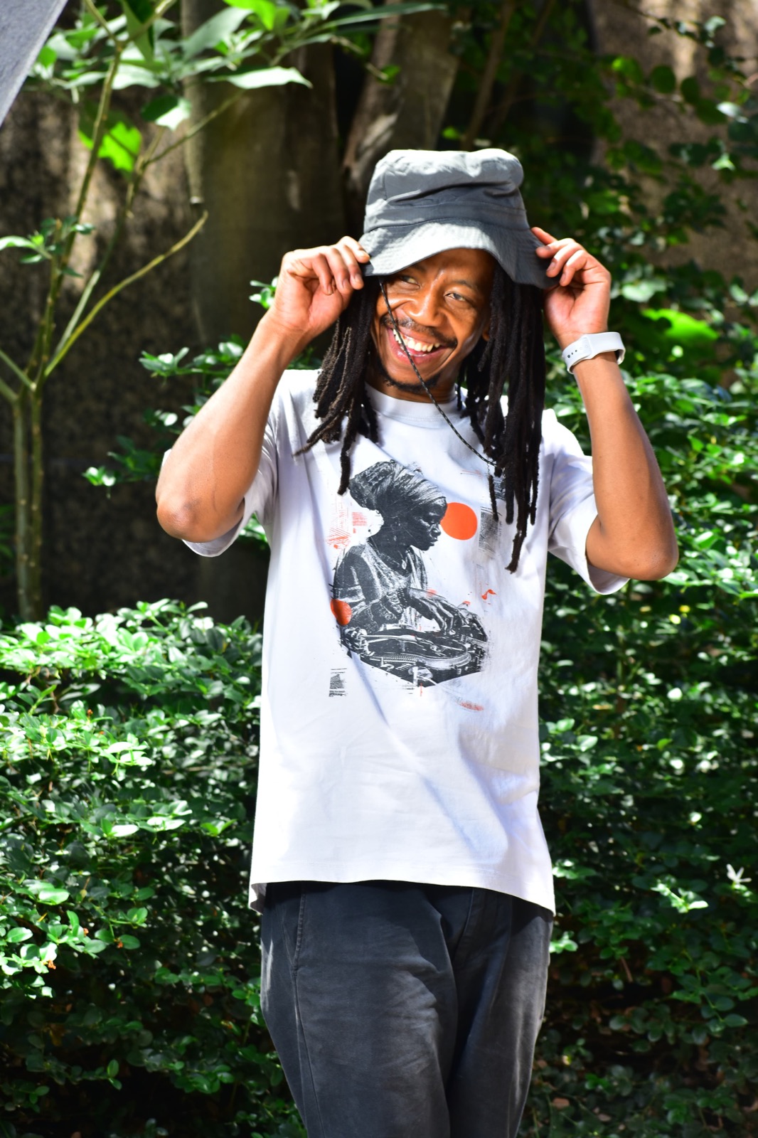 Darkie laughing, holding the brim of a grey bucket hat