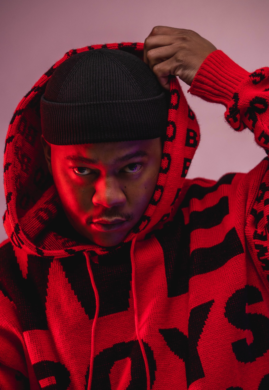 Mthizo in a red and black Boys of Soweto hoodie, hands at his hood