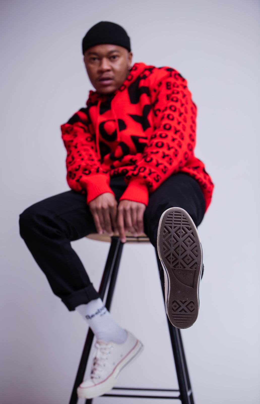 Mthizo seated on a stool in a red hoodie